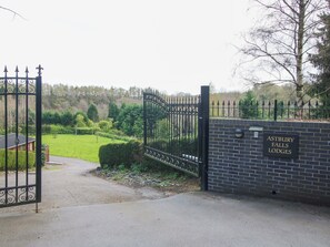 A gated entrance to Astbury Falls Lodges with a brick wall and a sign. - No.14 Astbury Falls Luxury Retreat (Bridgnorth)