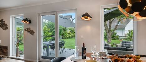 A dining area with a table set for two, a bottle of wine, and a vase of flowers.