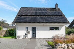 Ein Haus mit Solardach, einer kleinen Veranda und der Hausnummer 3.