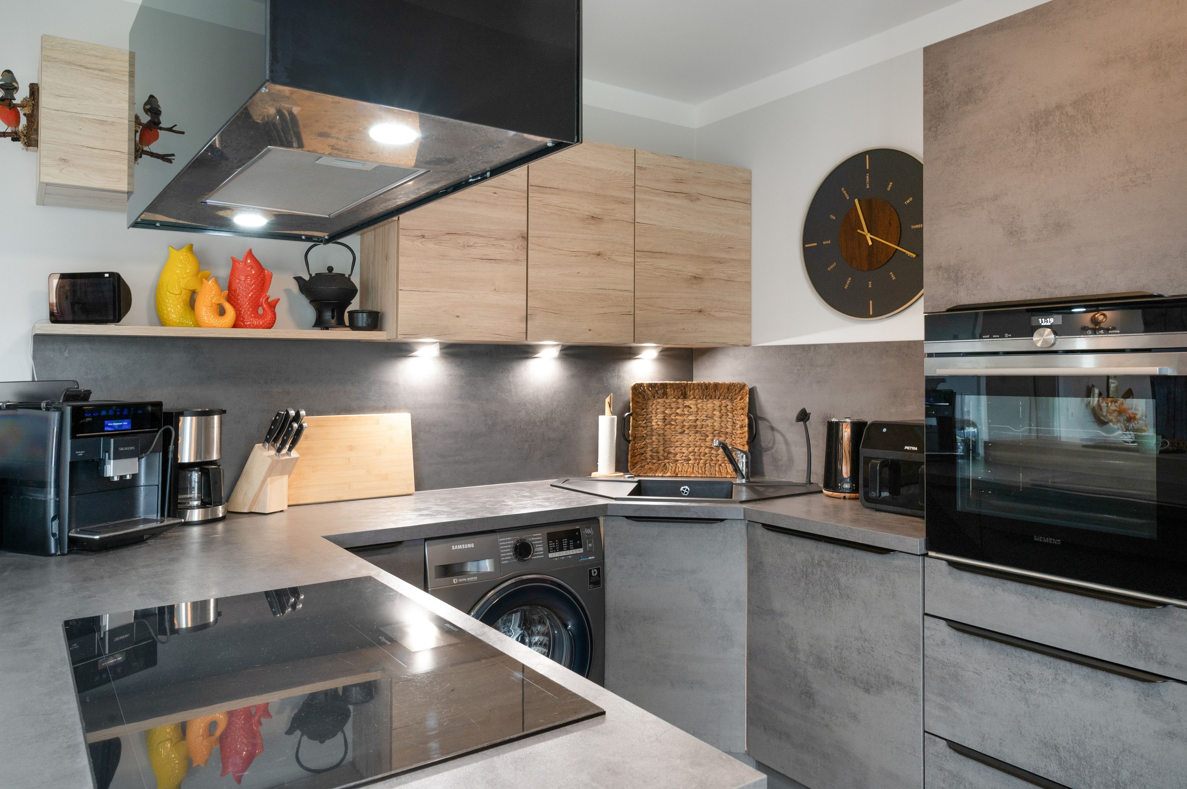 A modern kitchen with a built-in washing machine, a coffee machine, and a microwave.