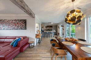 A modern living room with a red leather sofa, a dining area with wooden furniture, and a kitchen in the background.