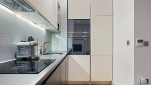 A modern kitchen with a built-in oven, a stovetop, and a microwave. - The Monument Retreat near Bank Station (London)