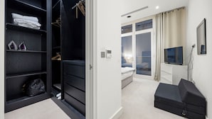A modern hotel room with a walk-in closet, a bed, a TV, and a seating area. - The Monument Retreat near Bank Station (London)