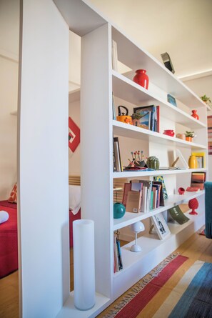 A white bookshelf with various decorative items and books. - Adenzia Apartment (Palermo)