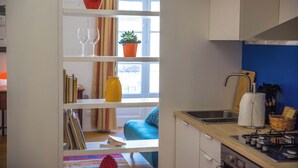 A kitchen with a gas stove, a sink, and a window with curtains. - Adenzia Apartment (Palermo)