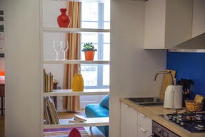A kitchen with a gas stove, a sink, and a window with curtains. - Adenzia Apartment (Palermo)