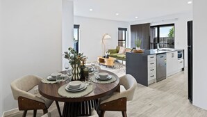 A modern kitchen with a dining area, featuring a round table with chairs, a sofa, and a lamp.
