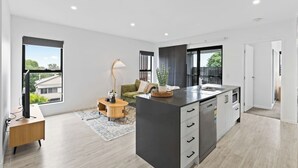 A modern kitchen with a central island, a dining area with a sofa, and large windows.