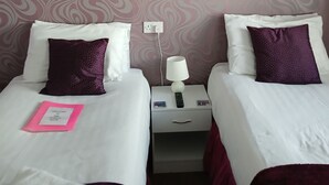 A hotel room with two beds, a nightstand, a lamp, and a power outlet on the wall. - Room-charming BnB Retreat in East Riding (Withernsea)