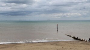 A beach with a wooden jetty extending into the water, a cloudy sky, and wind turbines in the distance. - Room-charming BnB Retreat in East Riding (Withernsea)