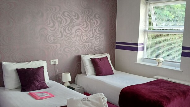 A hotel room with two beds, a window with blinds, a ceiling light, and a small rug. - Room-charming BnB Retreat in East Riding (Withernsea)