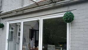 A house with a large sliding glass door leading to an outdoor dining area with a table and chairs. - Room-charming BnB Retreat in East Riding (Withernsea)