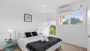Une chambre à coucher avec un lit, des lampes de chevet, une fenêtre donnant sur un beau paysage et un appareil de climatisation.