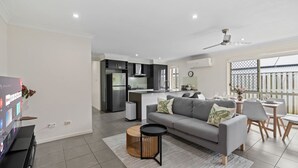 Ein modernes Wohnzimmer mit grauem Sofa, Couchtisch und Fernseher.