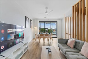Ein modernes Wohnzimmer mit Flachbildfernseher, Essbereich und Sofa.