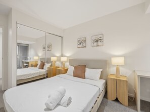 Ett modernt hotellrum med en stor säng, sängbord, ett skrivbord och en spegel.