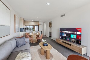 Een moderne woonkamer met een bank, salontafel, televisie en een eethoek.