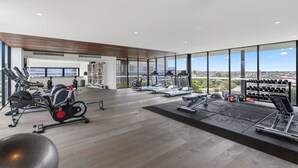 Un gimnasio moderno con máquinas de cardio, equipo de levantamiento de pesas y vistas a la ciudad.