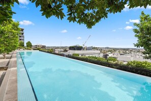 En pool på taket med fri utsikt över stadsbilden och byggkranar i bakgrunden.