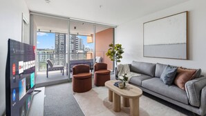 Una sala de estar moderna con un sofá gris, dos sillones marrones, una mesa de centro y un televisor.