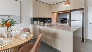 Una cocina moderna con una isla central, electrodomésticos de acero inoxidable y un comedor con una mesa redonda y sillas.