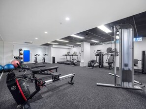 Ein Fitnessraum mit unterschiedlichen Trainingsgeräten, darunter Laufbänder, Crosstrainer und Kraftstationen.
