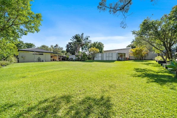 A well-maintained backyard with a lawn, a garage, and a shed.