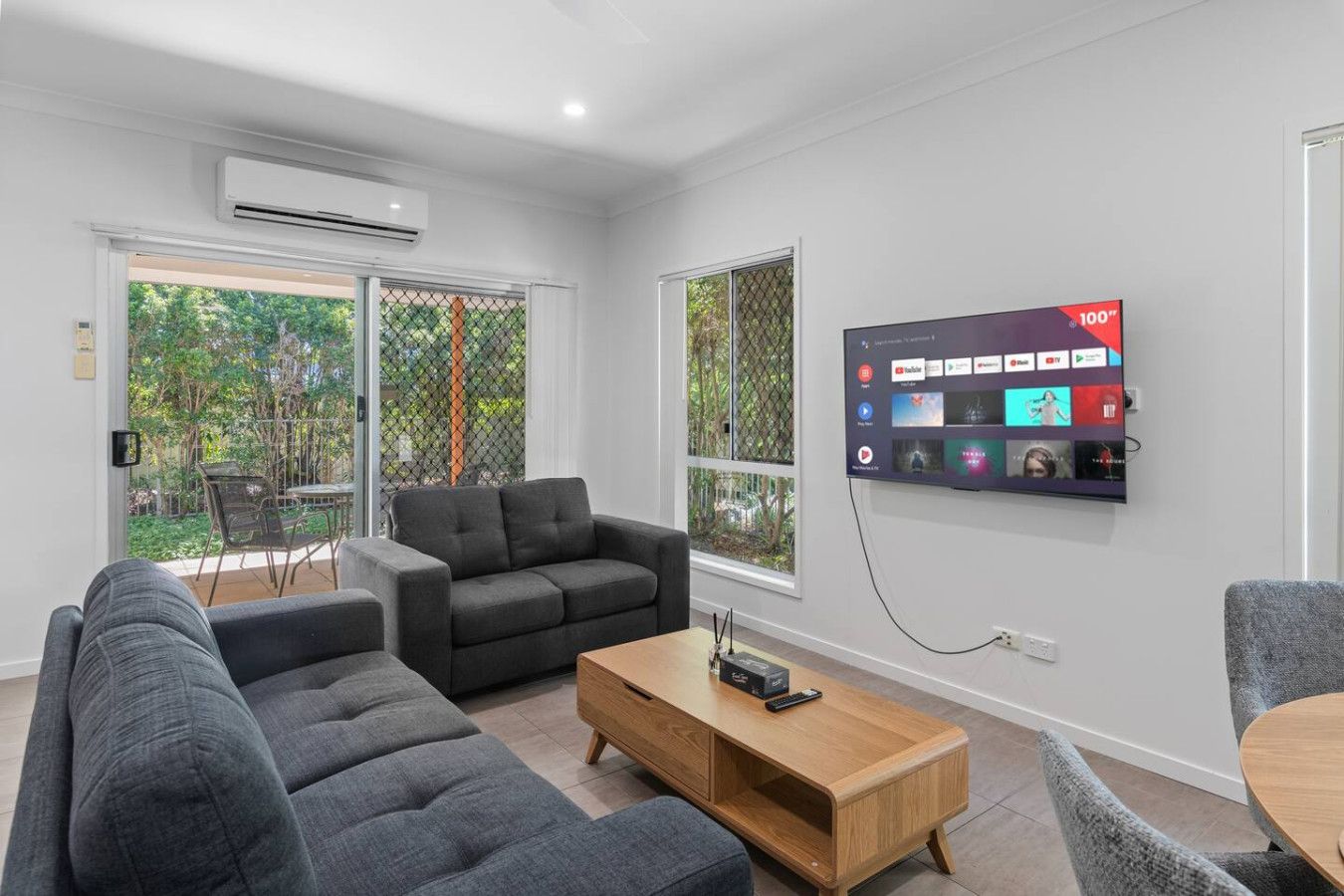Un soggiorno moderno con un divano, un tavolino da caffè e una TV montata a parete.