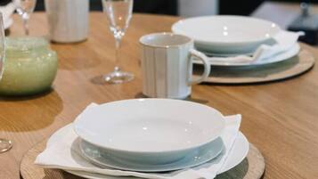 A dining table set with plates, a mug, and a glass.