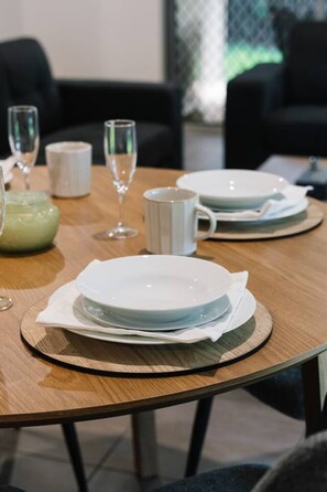 A dining table set with plates, a mug, and a glass. - Comfort Nest|2BR Quiet Comfort Retreat for Relax (Mount Warren Park)