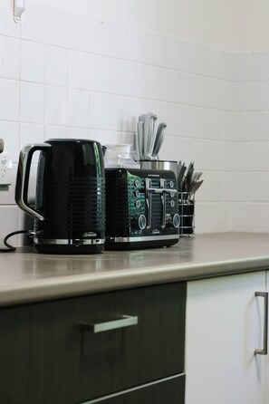 A kitchen with a coffee maker, a blender, and a utensil holder on the counter. - Comfort Nest|2BR Quiet Comfort Retreat for Relax (Mount Warren Park)