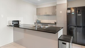 A modern kitchen with a black countertop, stainless steel appliances, and light-colored cabinetry. - 4BR Family Retreat | AC Throughout & Spacious (Park Ridge)
