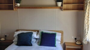 A neatly made bed with white linens, two pillows with green trim, and a wooden headboard. - Josephine Nb37 (Newquay)