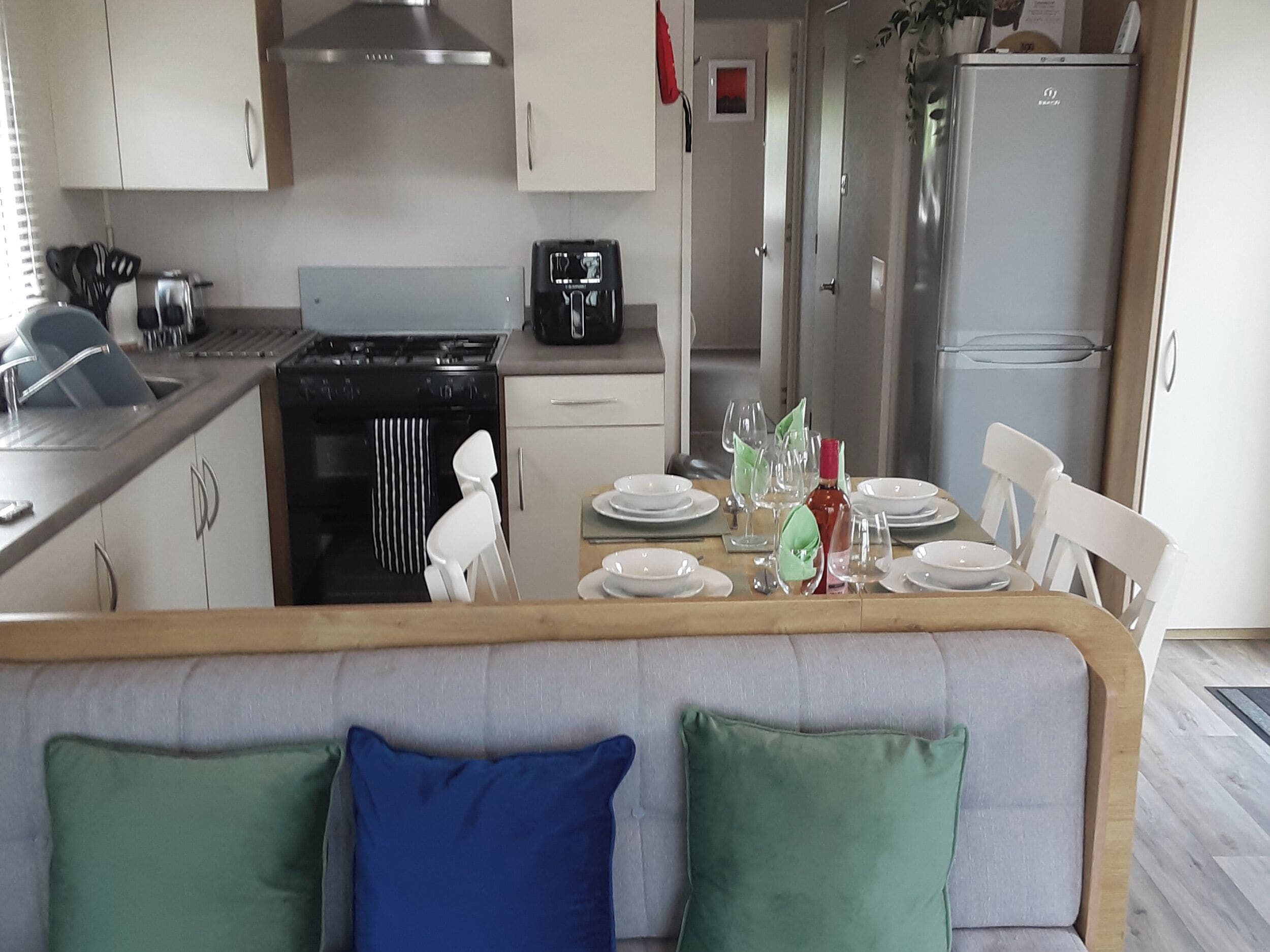 Une cuisine moderne avec des meubles blancs, une cuisinière noire et un réfrigérateur.