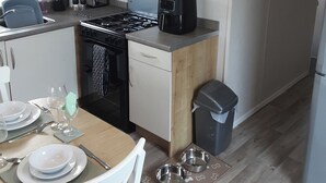 A compact kitchen with a stove, dishwasher, and a trash bin. - Josephine Nb37 (Newquay)