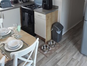 A compact kitchen with a stove, dishwasher, and a trash bin. - Josephine Nb37 (Newquay)