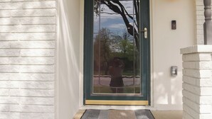 A front door with a glass panel, a doormat, a wall-mounted light fixture, and a small window. - Family-Friendly 3 Bedroom/2 Bath Home - 25 Min to Dallas w/ Free EV Charging (Forney)