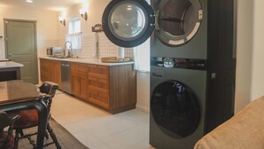 A kitchen with a washing machine, a dining table, and wooden cabinets. - Family-Friendly 3 Bedroom/2 Bath Home - 25 Min to Dallas w/ Free EV Charging (Forney)