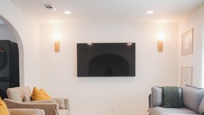 A living room with two sofas, a coffee table, and a flat-screen TV mounted on the wall. - Family-Friendly 3 Bedroom/2 Bath Home - 25 Min to Dallas w/ Free EV Charging (Forney)