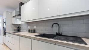 Uma cozinha moderna com armários brancos, uma pia preta e um revestimento de azulejos.