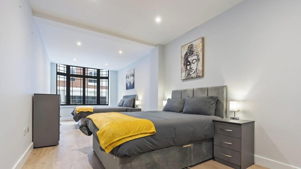 Quarto moderno com uma cama grande, mesas de cabeceira e obras de arte nas paredes.