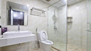 A modern bathroom with a white sink, a toilet, a glass-enclosed shower, and a mirror above the sink. - Boho Apartment Tay Ho (Hanoi)