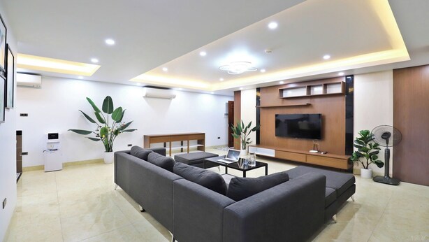 A modern living room with a sofa, coffee table, TV, and plants. - Boho Apartment Tay Ho (Hanoi)