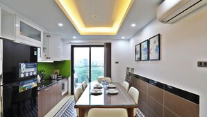 A modern kitchen with a dining area, featuring a large window, a dining table set for four, and a built-in kitchen counter. - Boho Apartment Tay Ho (Hanoi)
