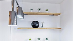 A modern kitchen with two wooden shelves, a black spherical vase, and a pendant light.