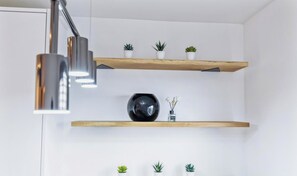 A modern kitchen with two wooden shelves, a black spherical vase, and a pendant light.