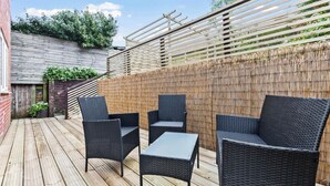 A patio with wicker furniture and a bamboo fence.