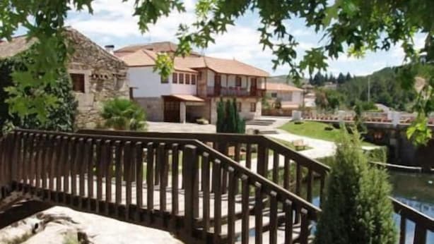 A stone building with a red roof, a wooden deck, and a small water feature.