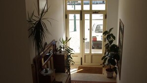 A hallway with a wooden bench, a potted plant, a door leading outside, and a patterned rug.