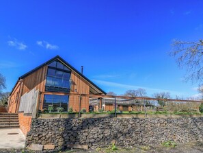 A modern two-story building with large windows and a stone retaining wall. - The Old Dairy (Honiton)